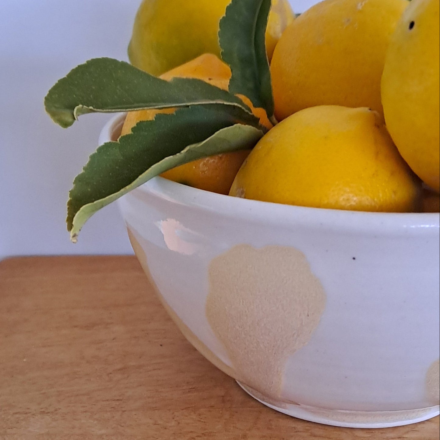 White bowl with lemons on a wooden surface