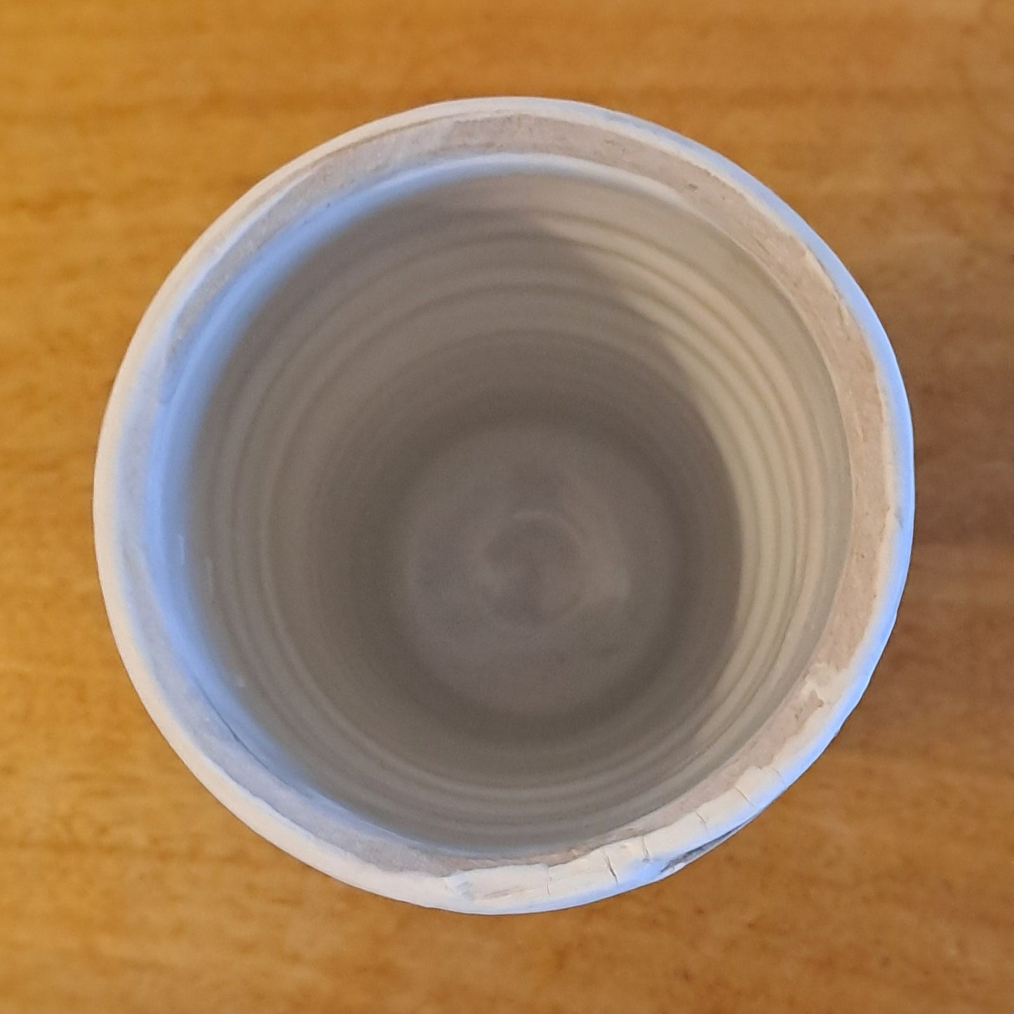 Wooden shelf with a cylindrical striped vase on a light background