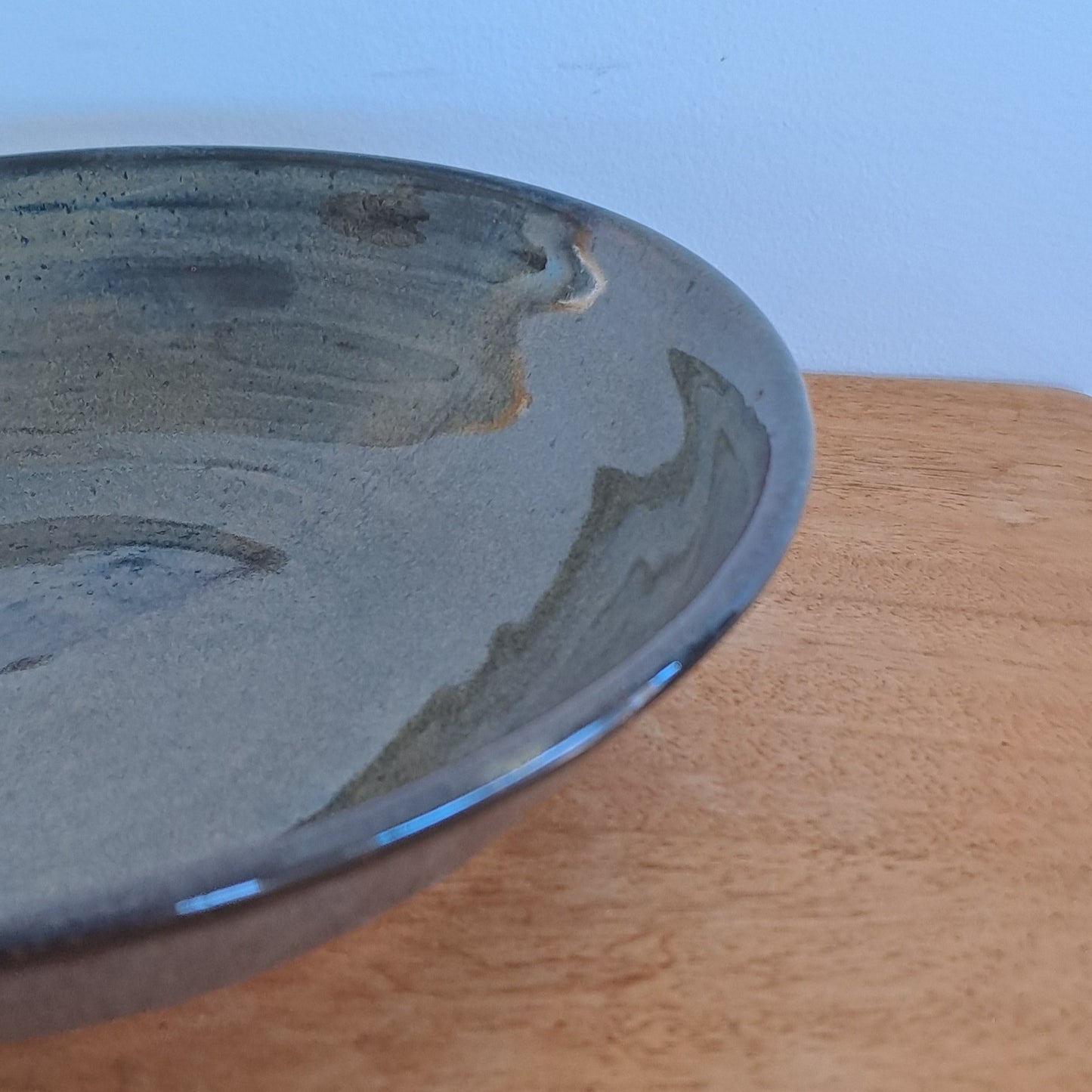 Close-up of a black bowl on a wooden door with a light blue background