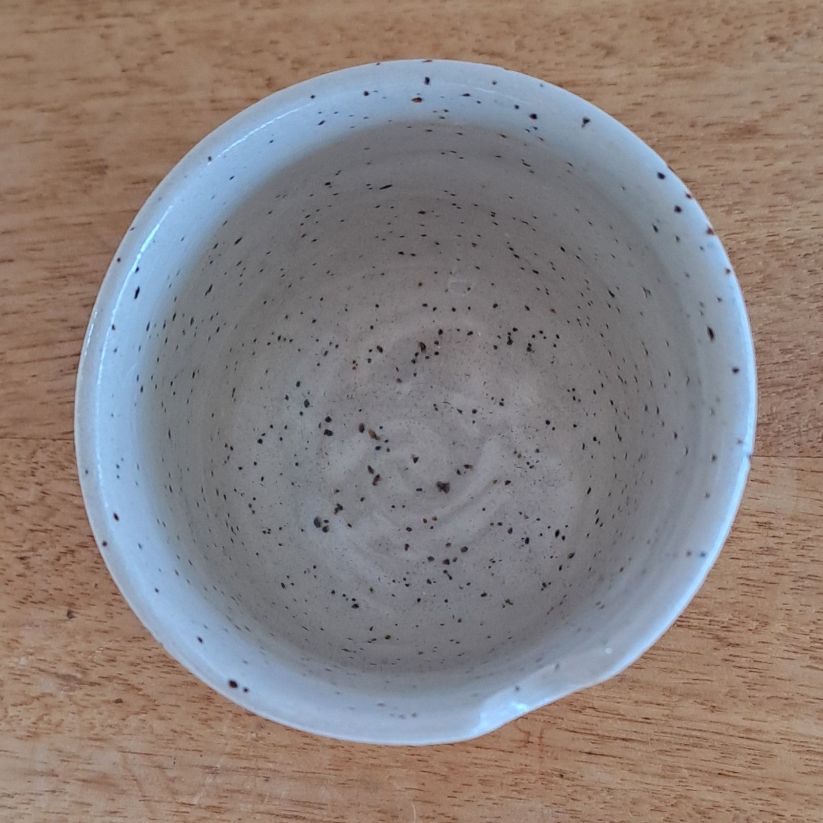 Speckled ceramic bowl on a wooden surface
