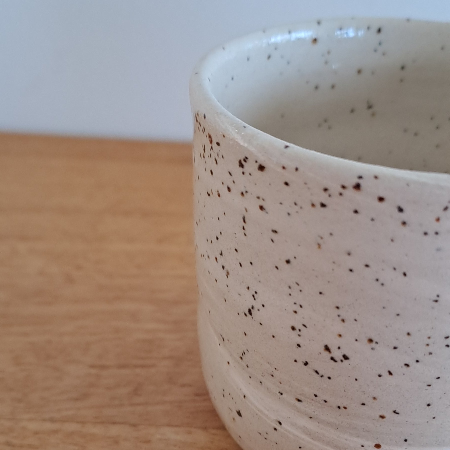 Speckled ceramic ring on a wooden surface with a white background