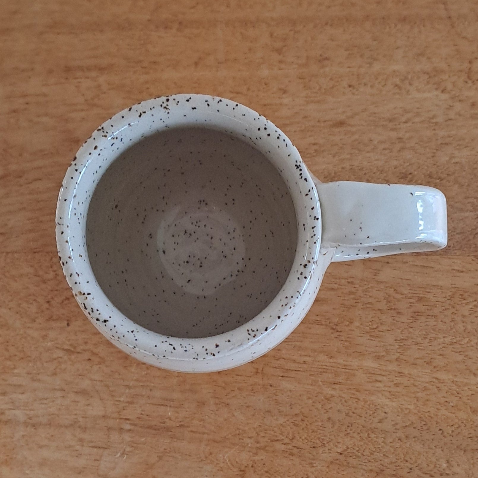 White ceramic mug with speckled design on a wooden surface