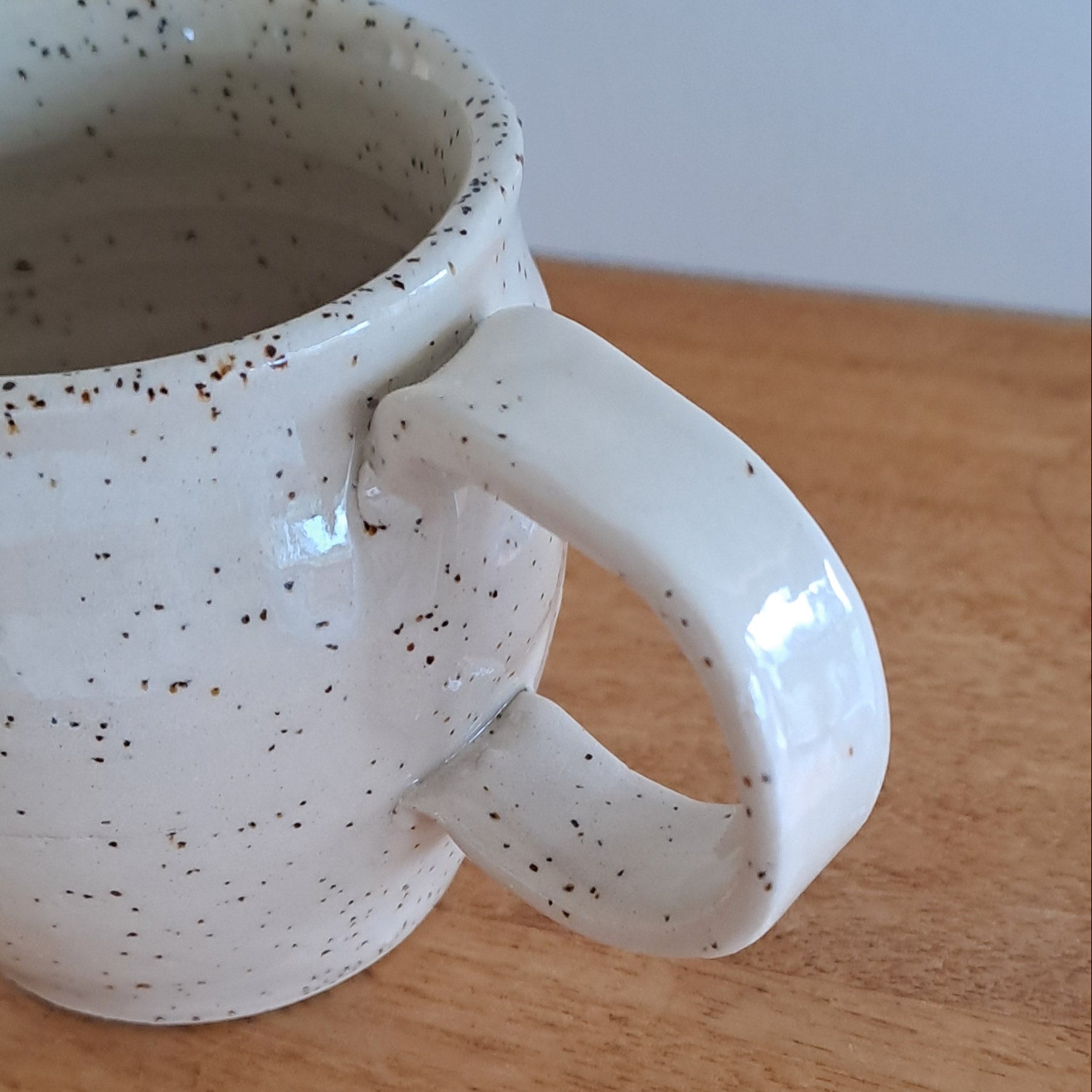 White ceramic mug with speckled pattern on a wooden surface