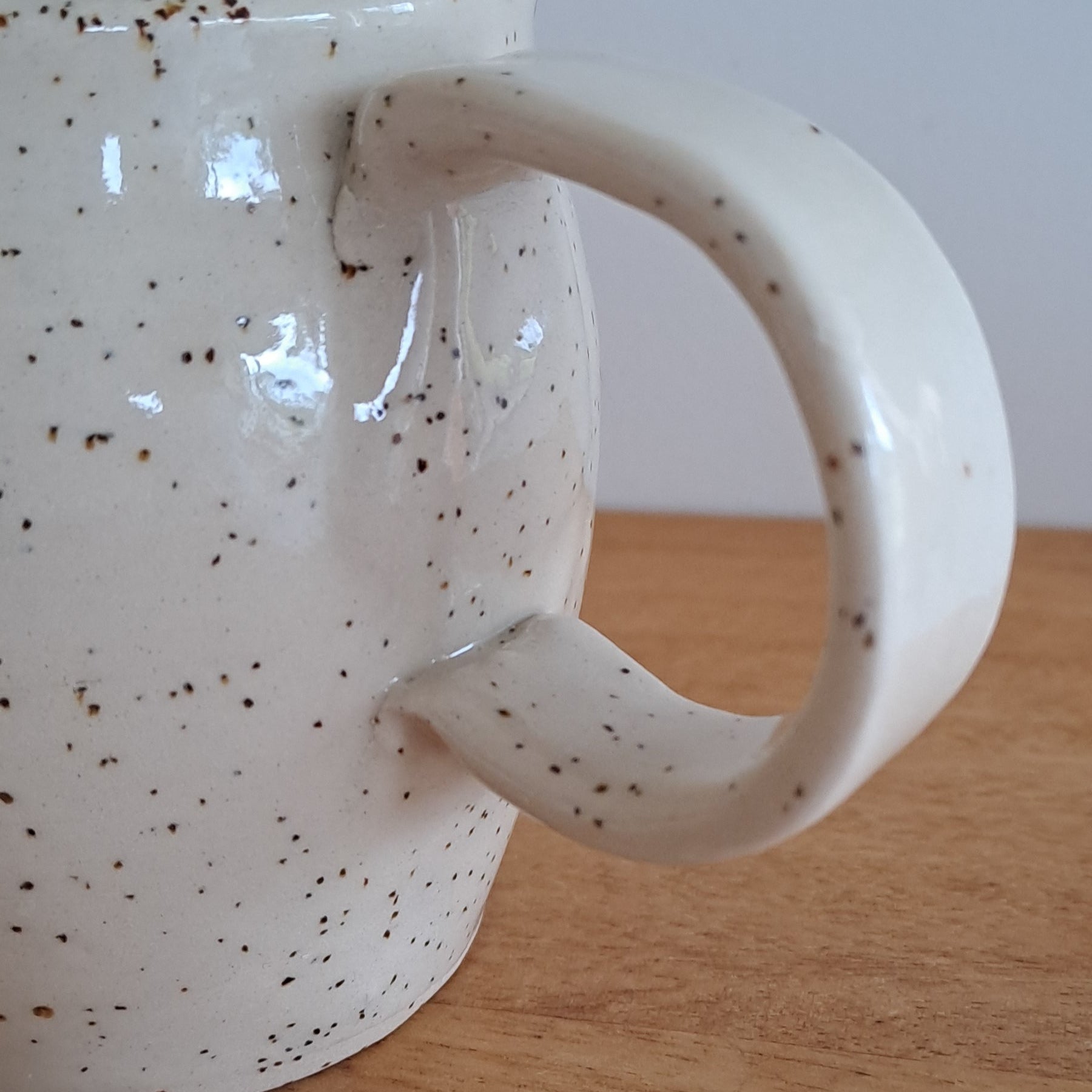 Speckled ceramic mug on a wooden surface with a white background
