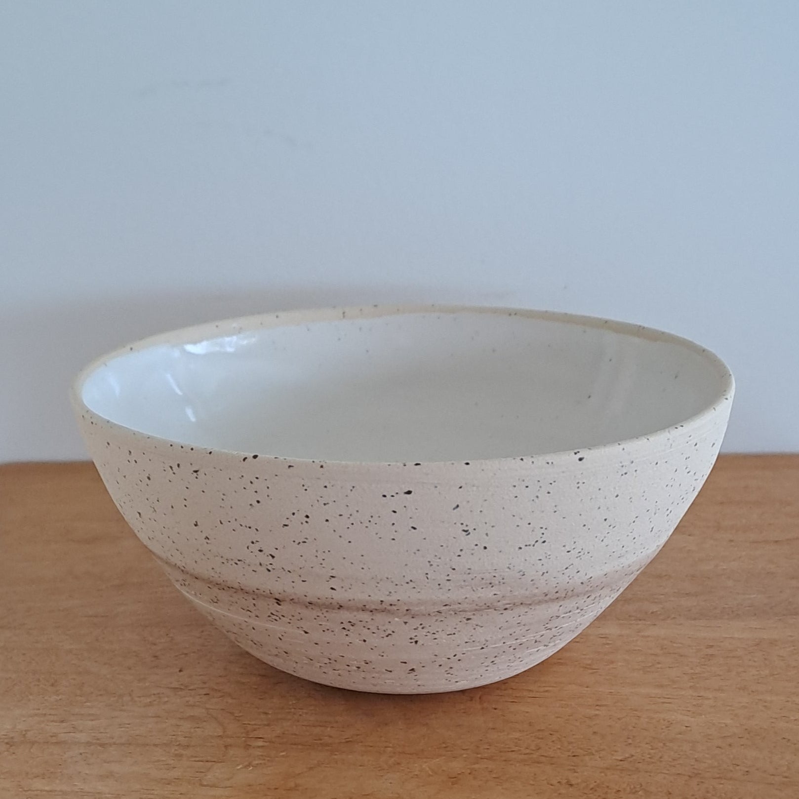 White ceramic bowl on a wooden surface with a light wall in the background