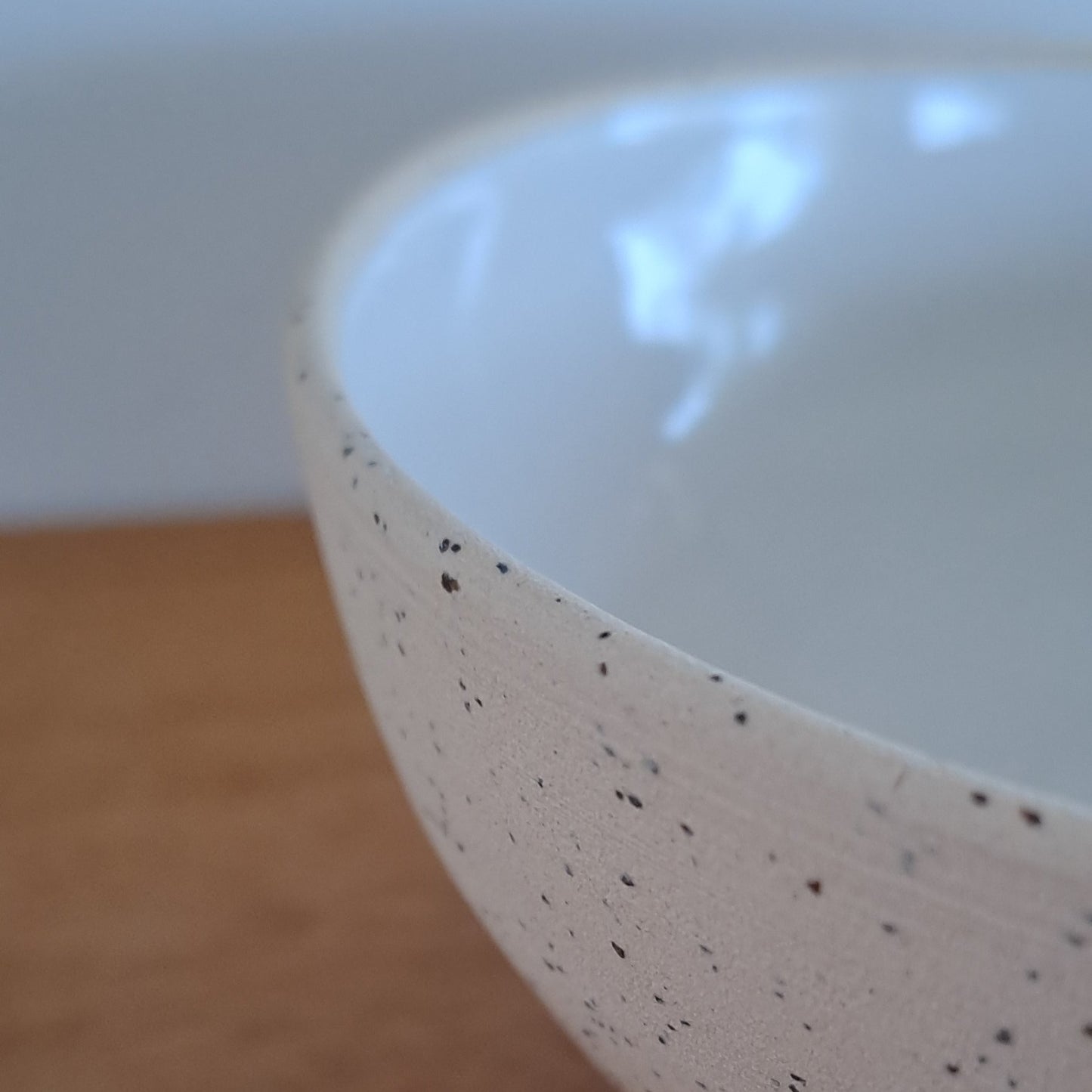 Close-up of a ceramic bowl with speckled pattern on a wooden surface