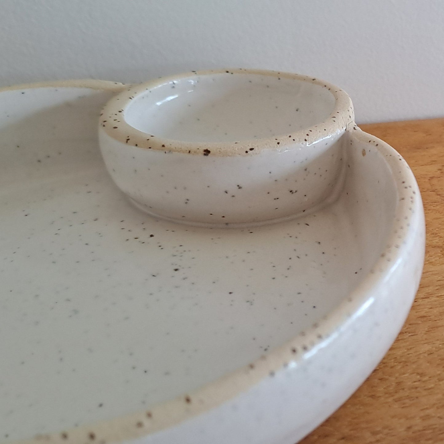 White ceramic dish with speckled pattern on a wooden surface