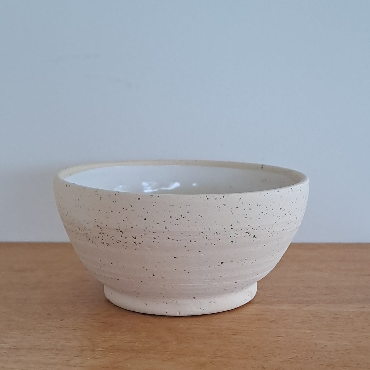 White ceramic bowl on a wooden surface with a light blue background