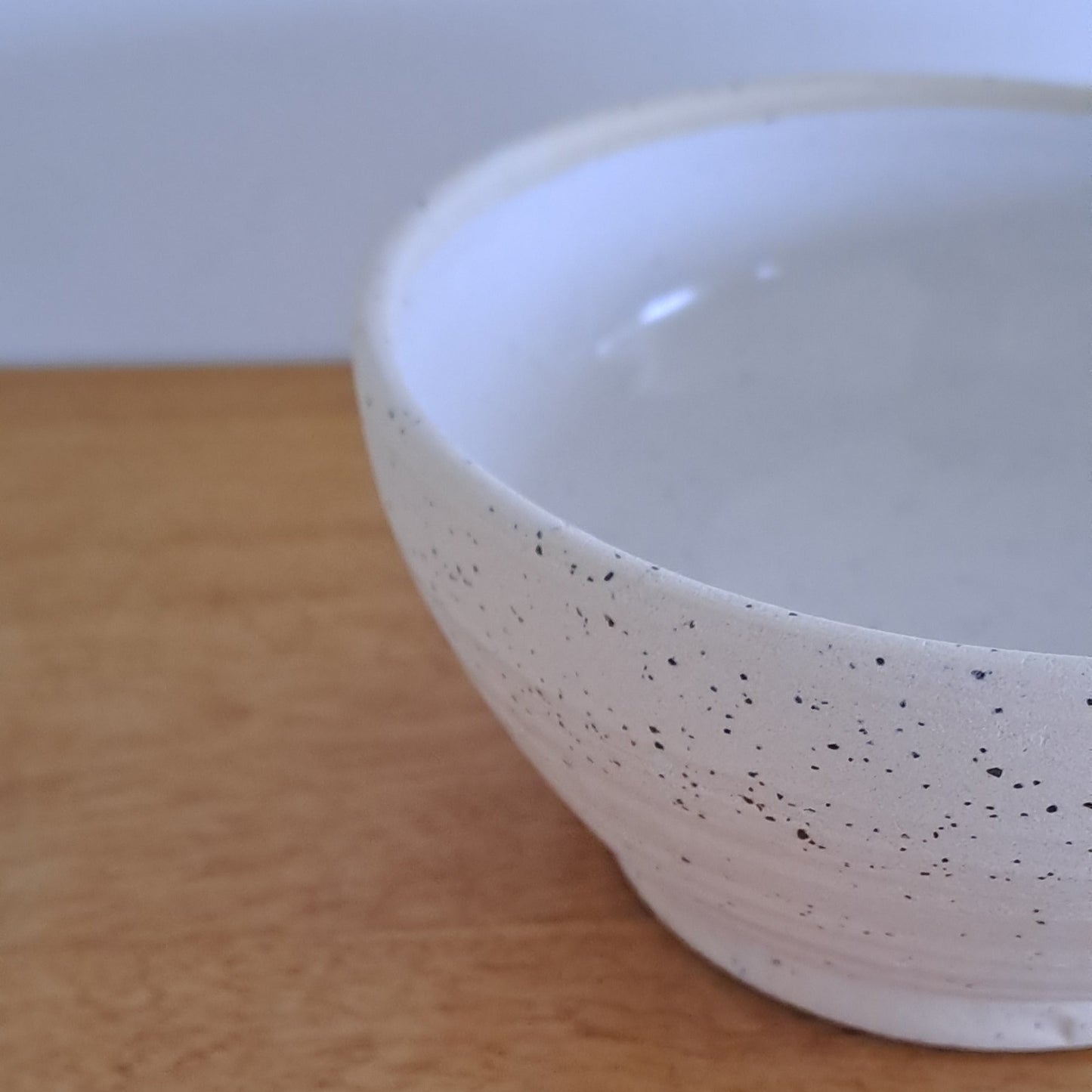 White ceramic bowl on a wooden surface with a white background
