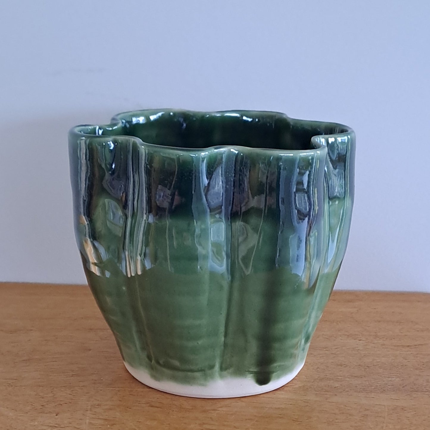 Green ceramic vase on a wooden surface with a white background