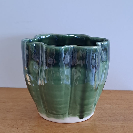 Green ceramic vase on a wooden surface with a white background