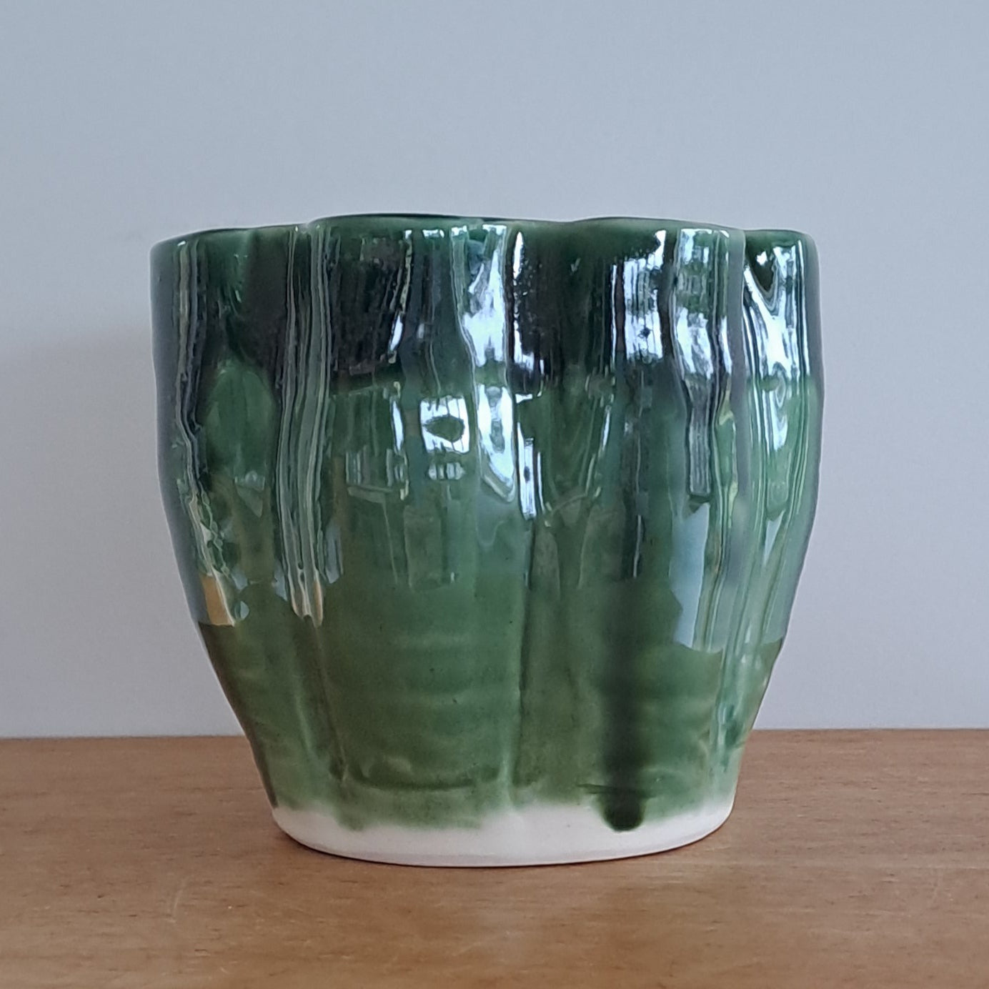 Green vase on a wooden surface with a white background