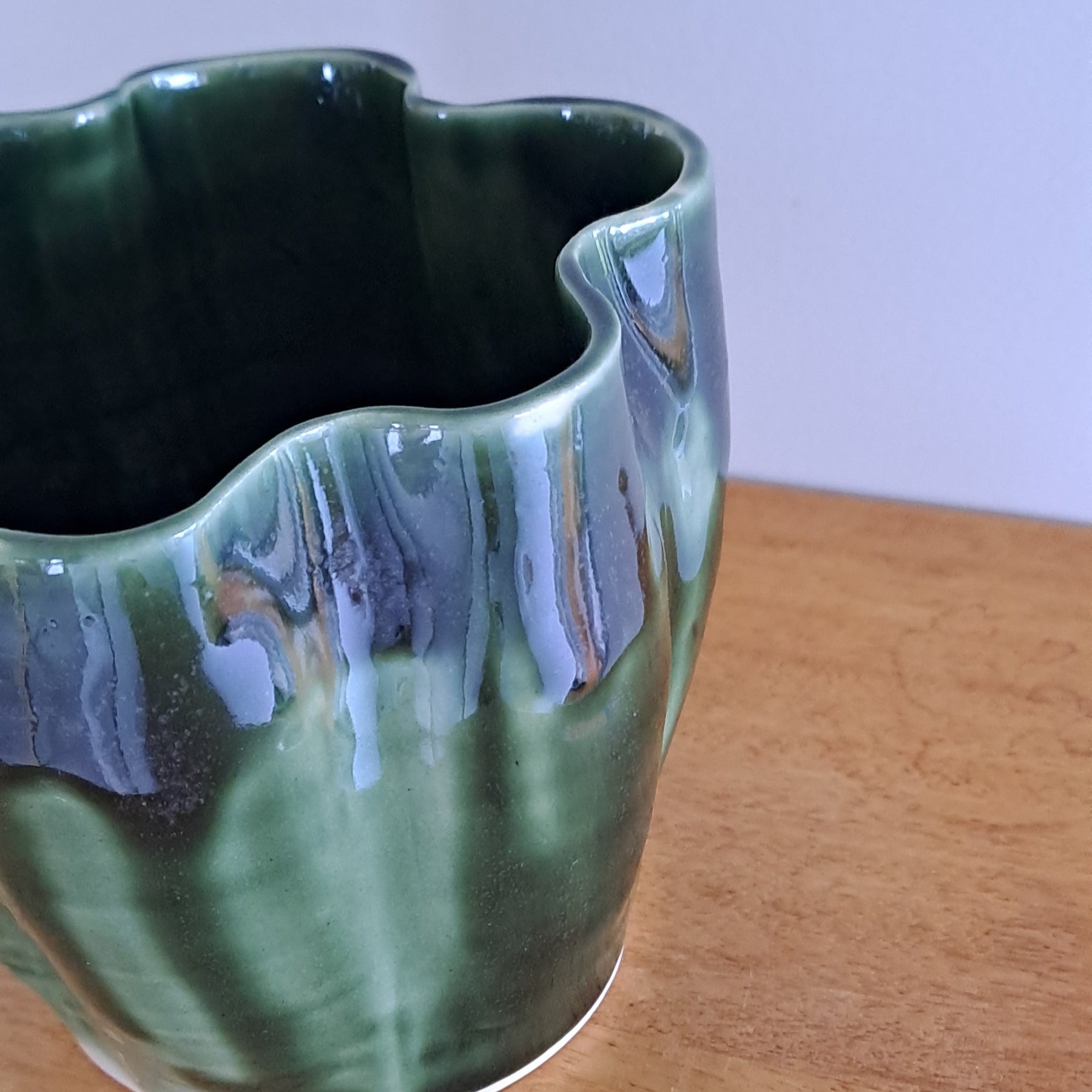 Green ceramic vase on a wooden surface with a white background