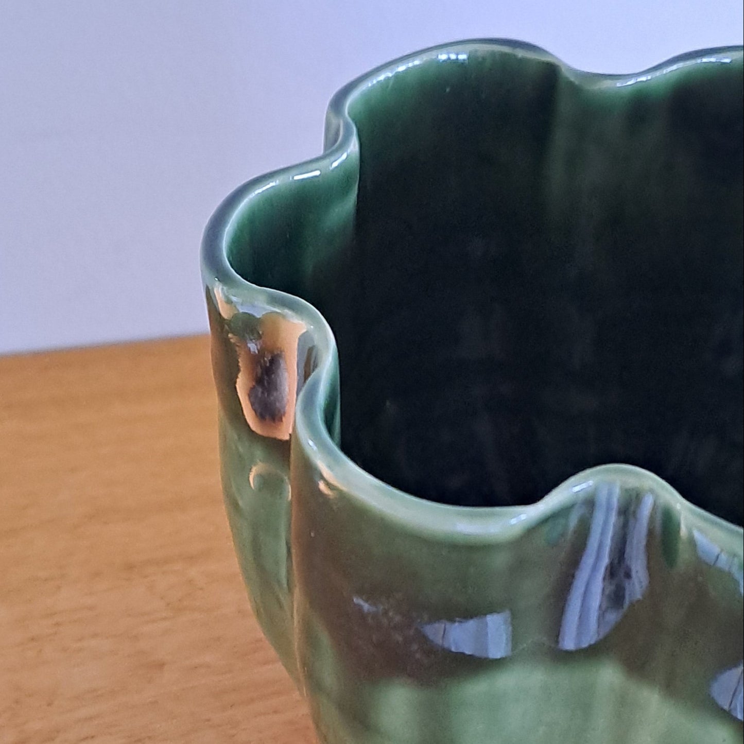 Green ceramic vase on a wooden surface with a white background