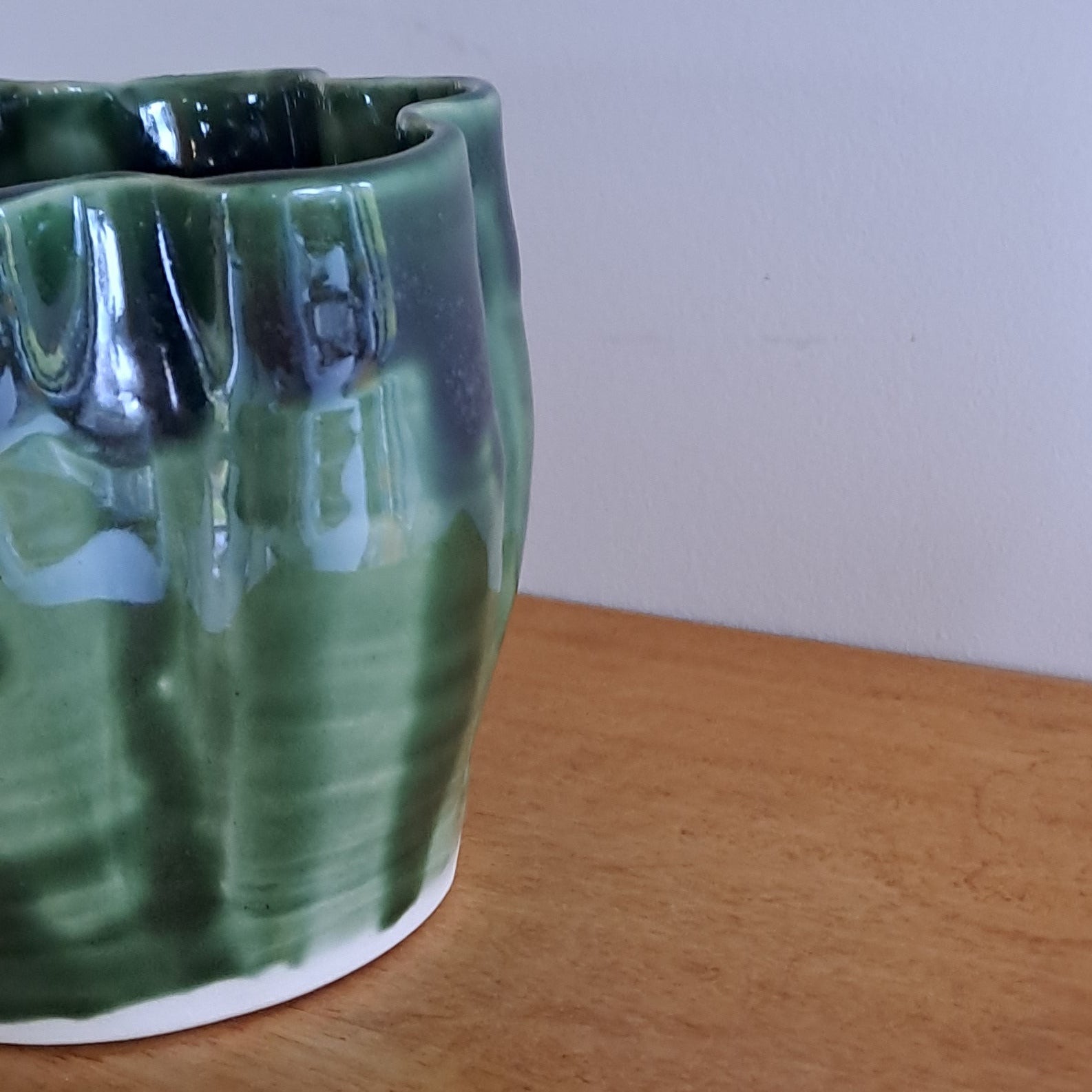Green ceramic vase on a wooden surface with a white background