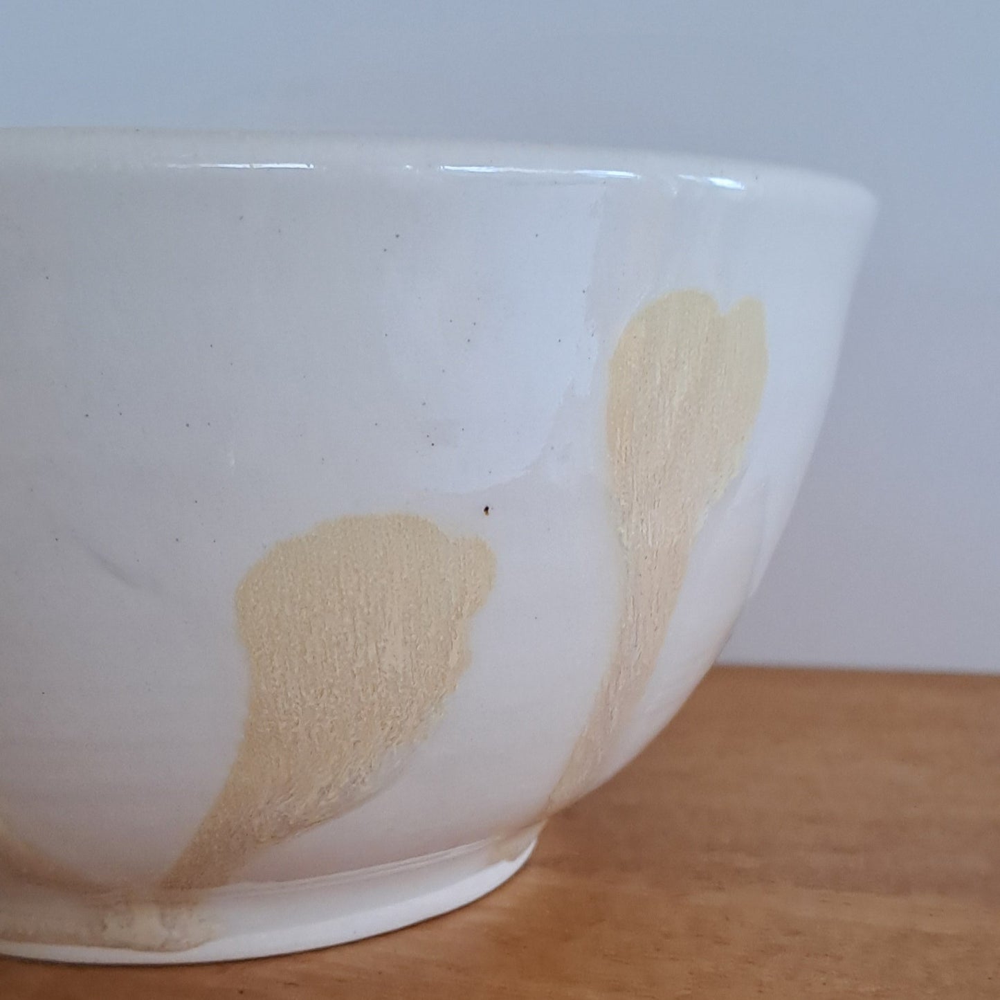 White ceramic bowl with gold patterns on a wooden surface