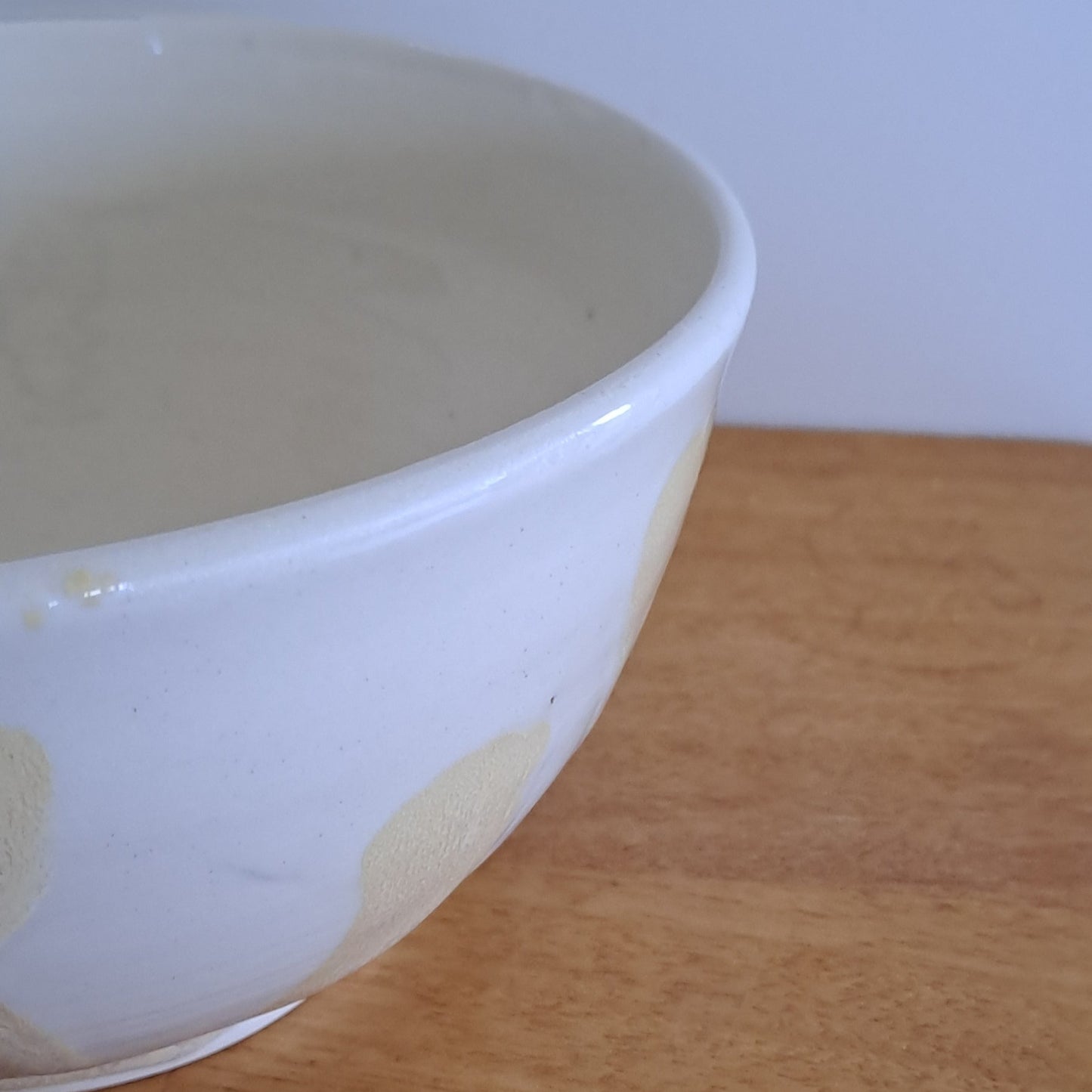 White ceramic bowl leaning against a wooden surface with a light blue background