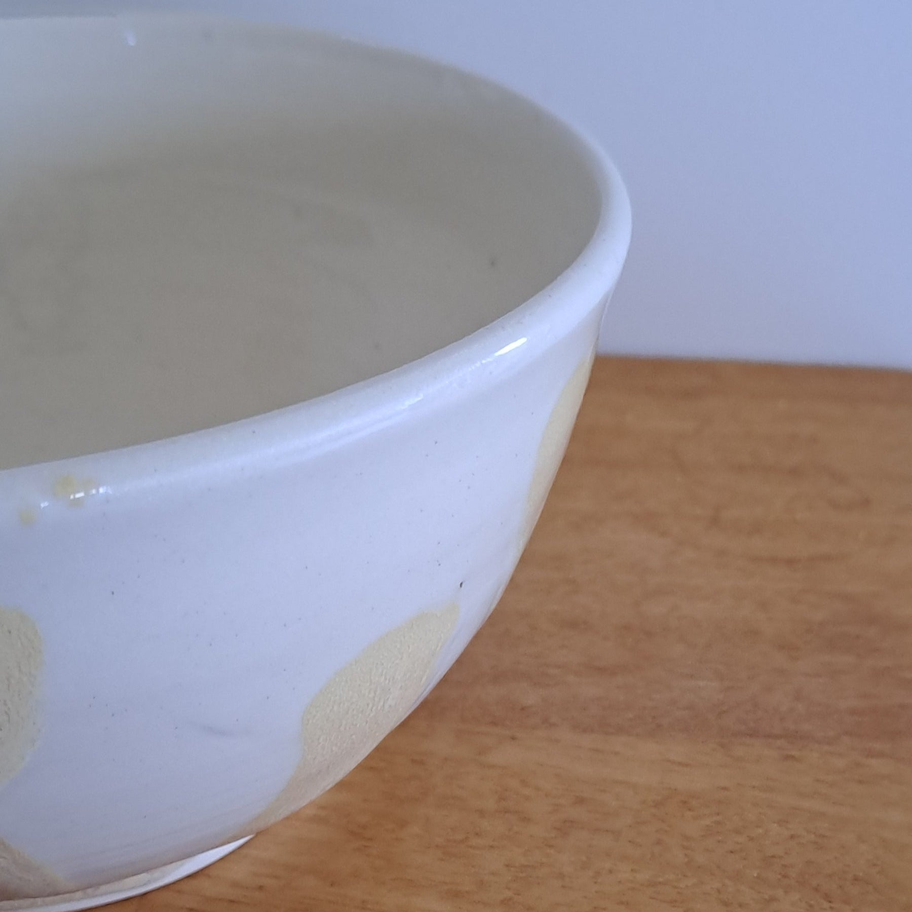 White ceramic bowl leaning against a wooden surface with a light blue background