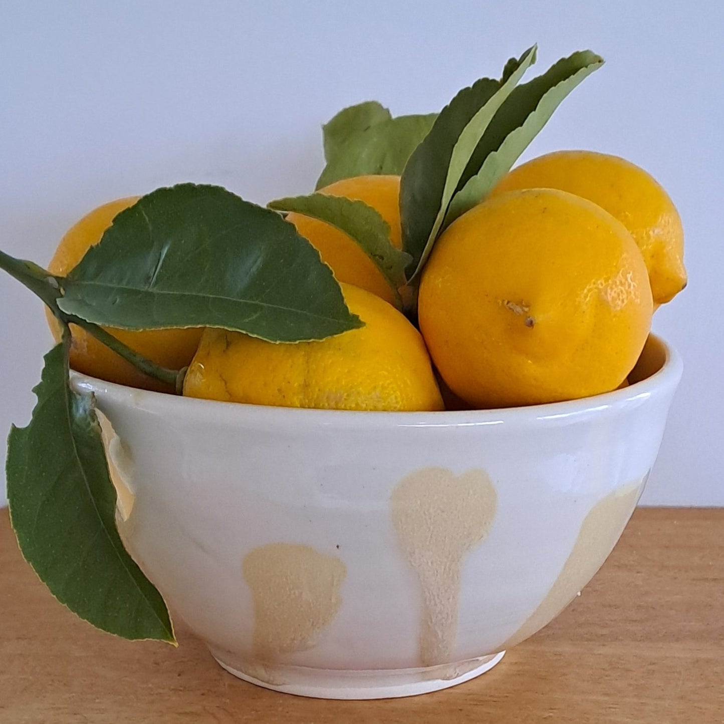 White bowl with gold hearts filled with lemons on a wooden surface