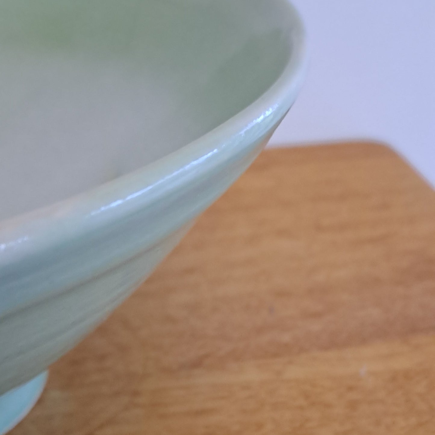 Ceramic bowl with a light green interior against a wooden background