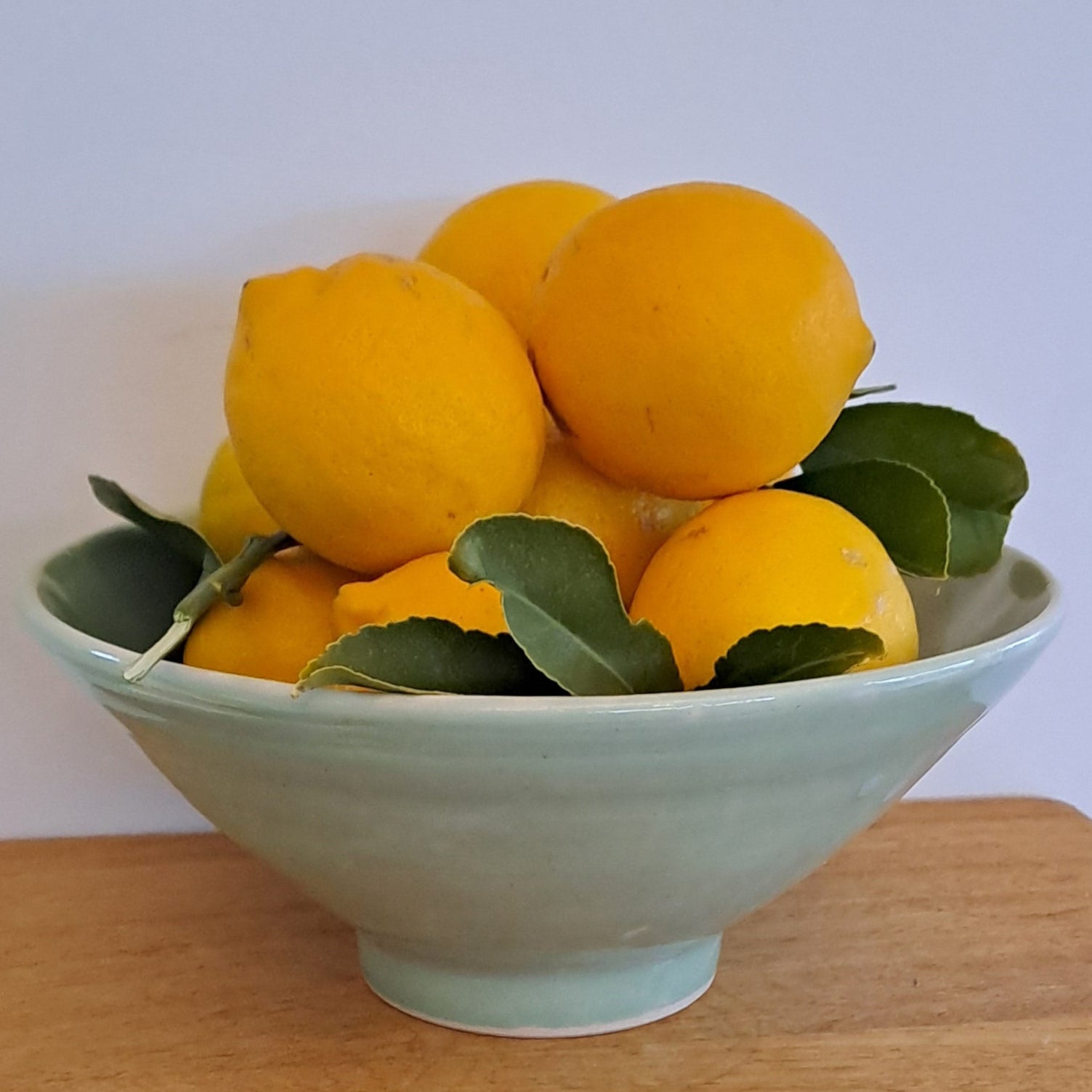 Bowl of lemons on a wooden surface with a light background