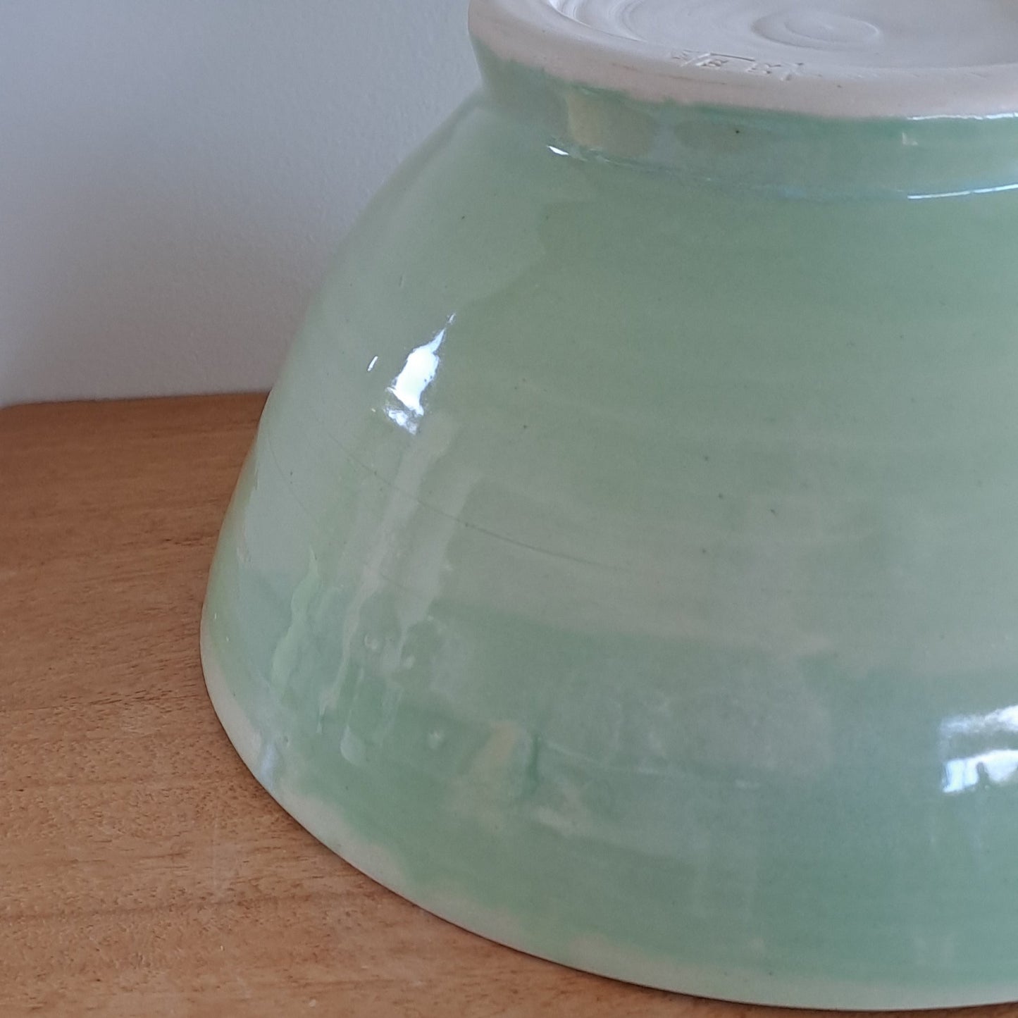 Green ceramic bowl on a wooden surface with a white background
