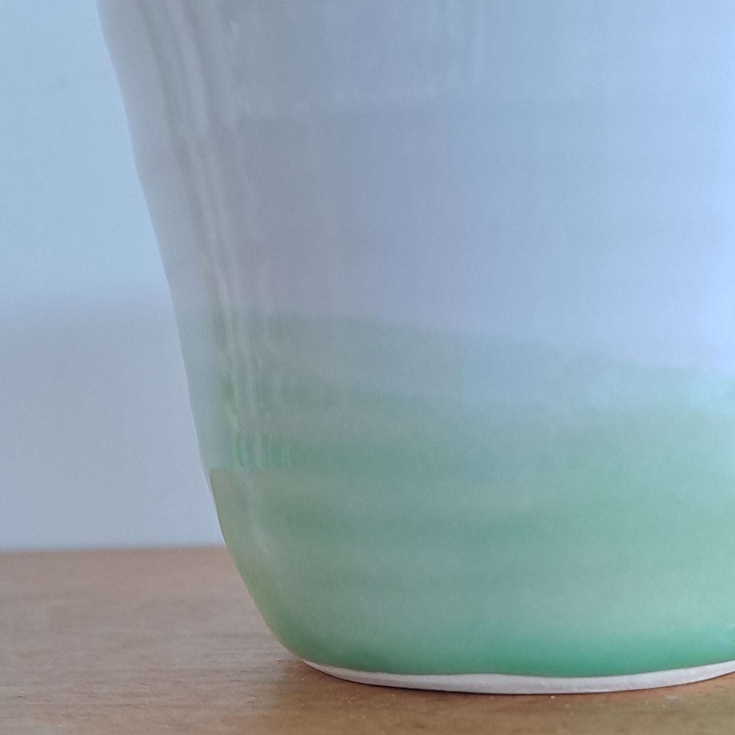 Close-up of a mug with a green rim on a wooden surface