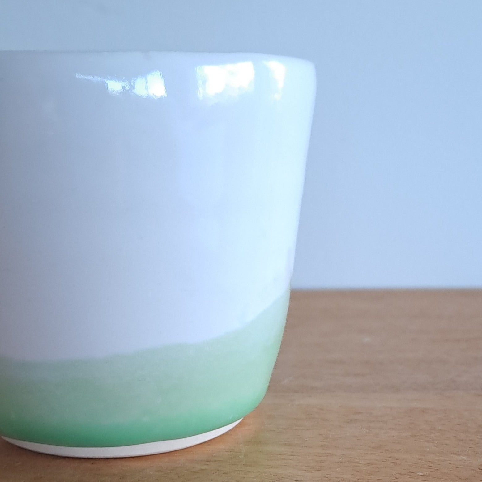 White cup with green rim on a wooden surface