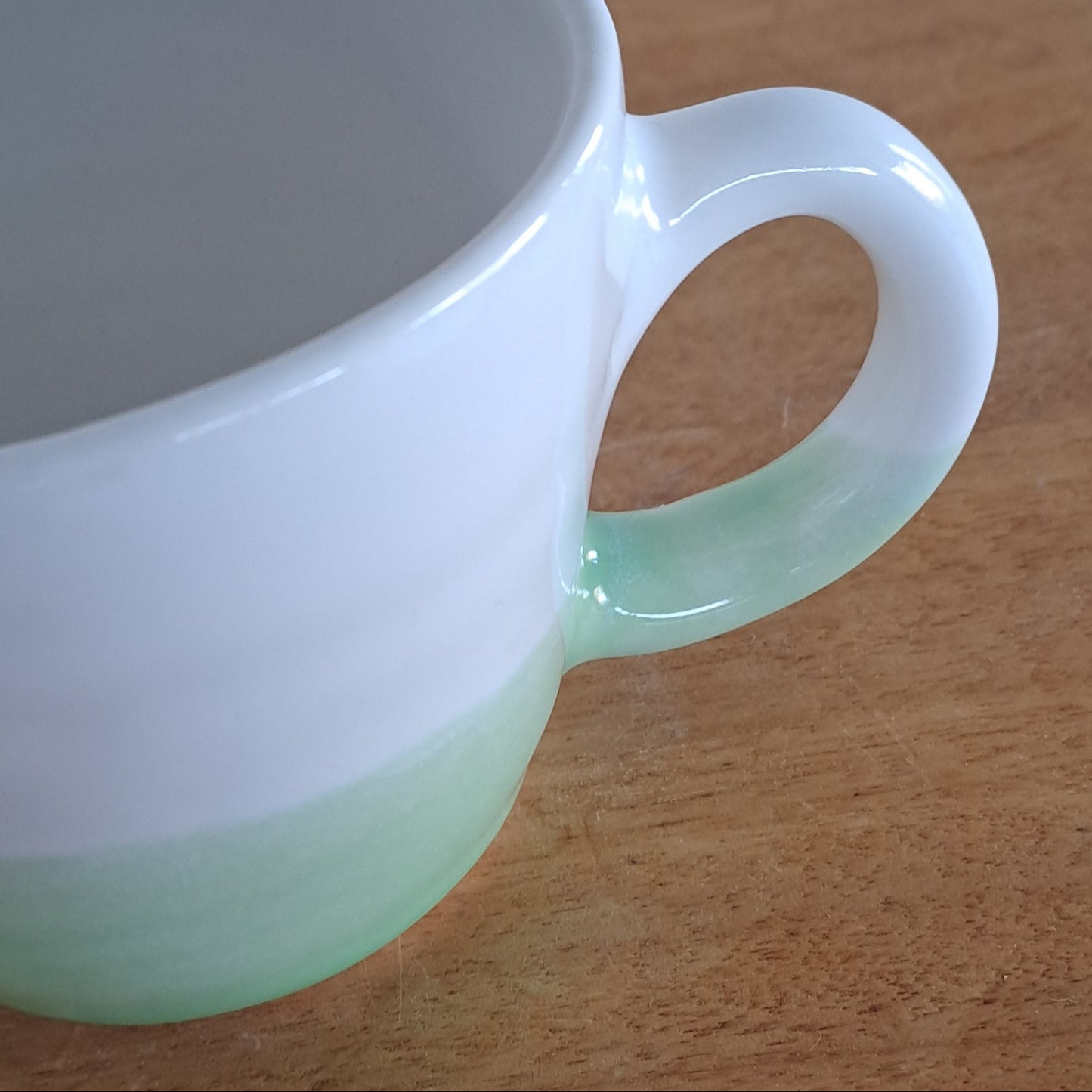 White mug with a green accent on a wooden surface