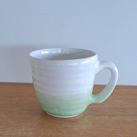 White mug leaning against a wooden surface 