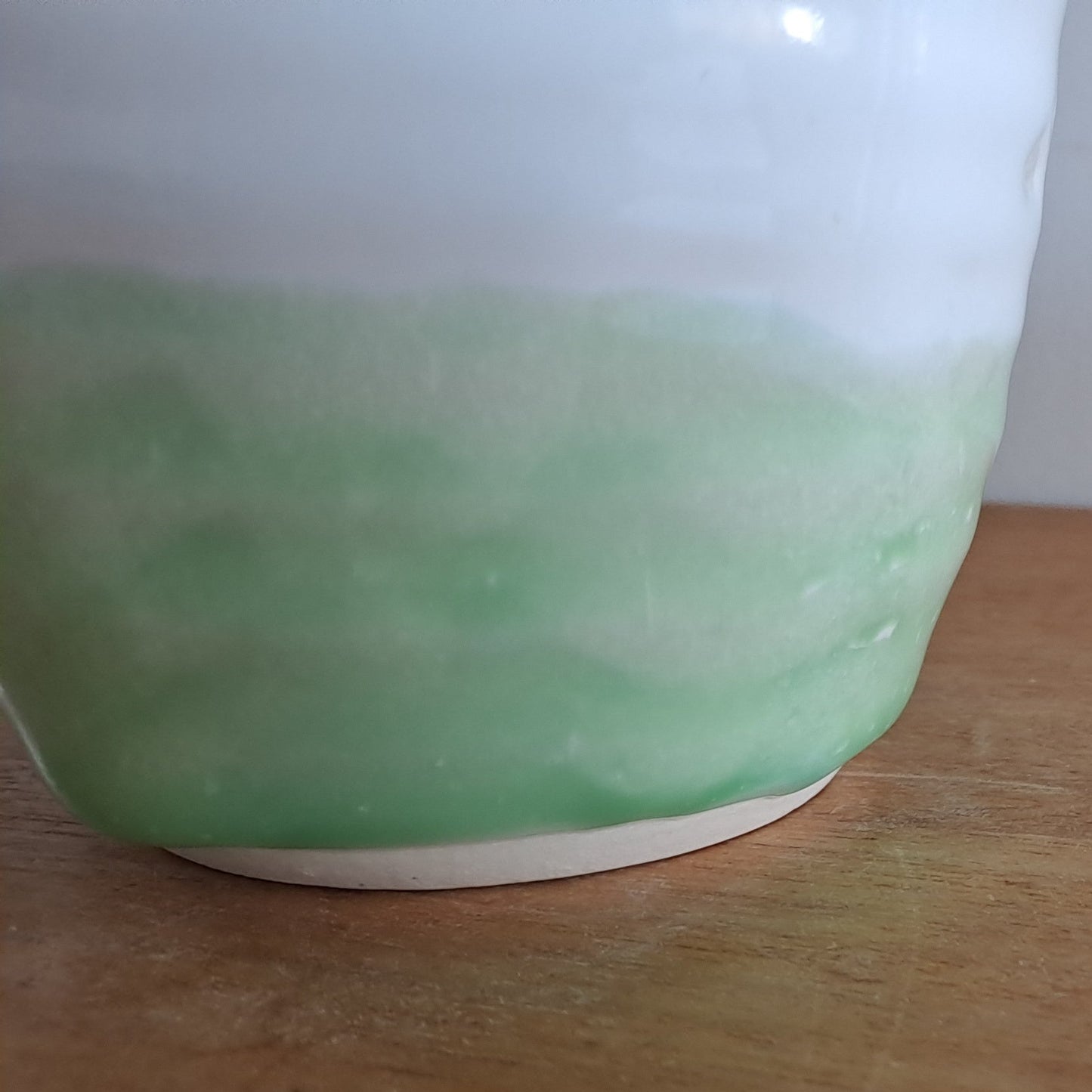 Green ceramic mug on a wooden surface with a white background