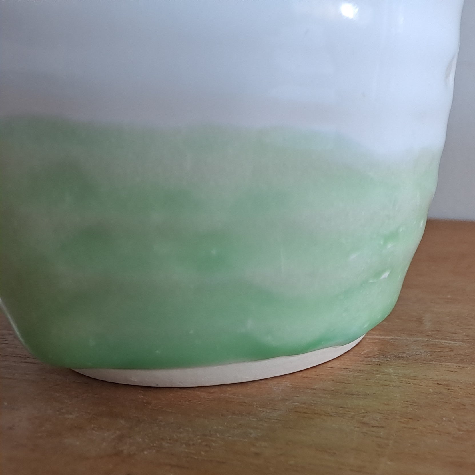 Green ceramic mug on a wooden surface with a white background