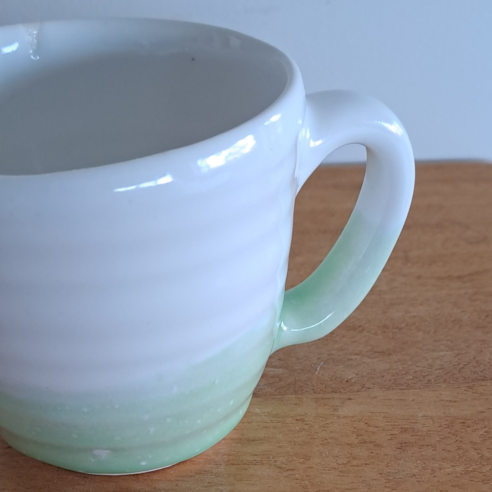 White mug with a green accent on a wooden surface