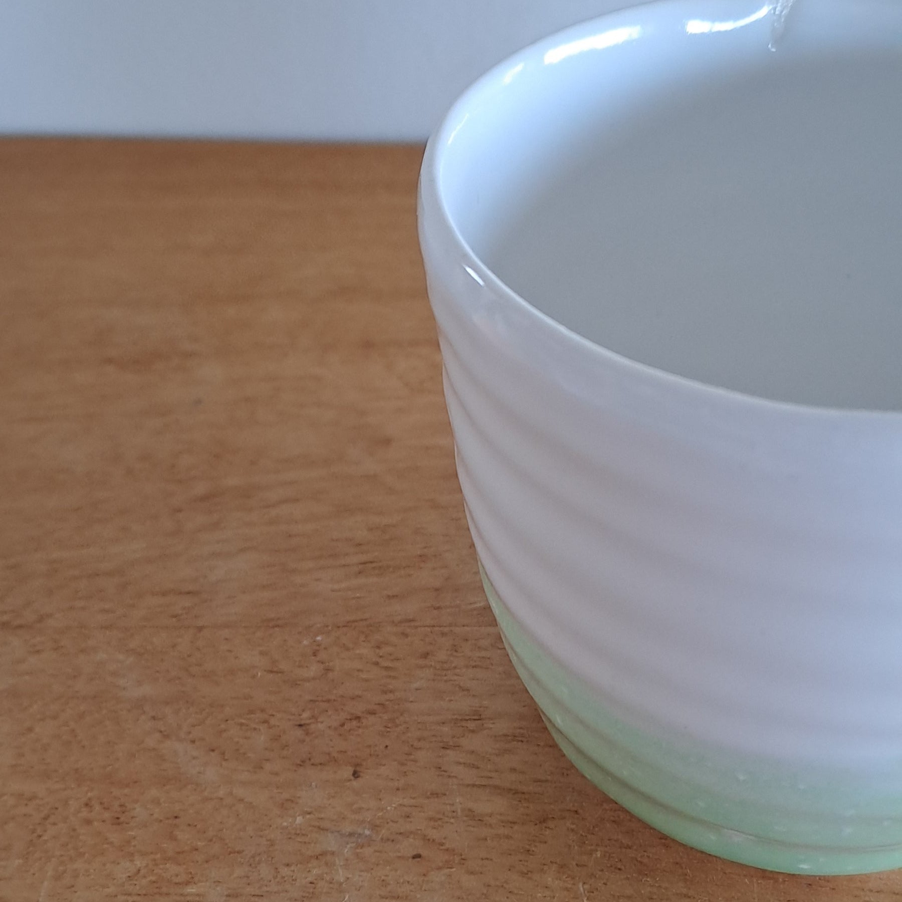 White mug with green rim on a wooden surface