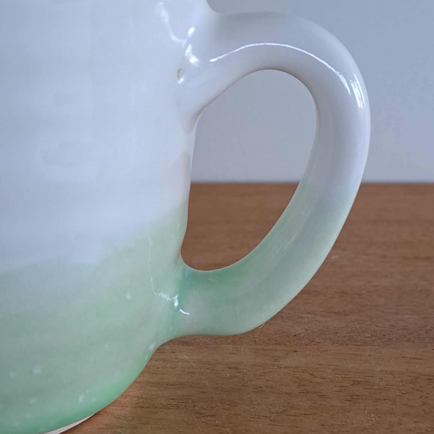 White ceramic mug with a handle against a wooden background