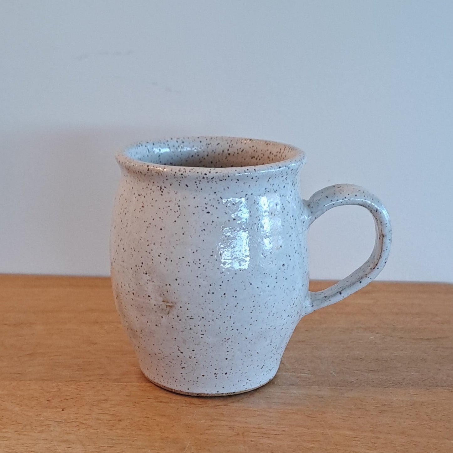 Ceramic mug with speckled texture attached to a wooden surface