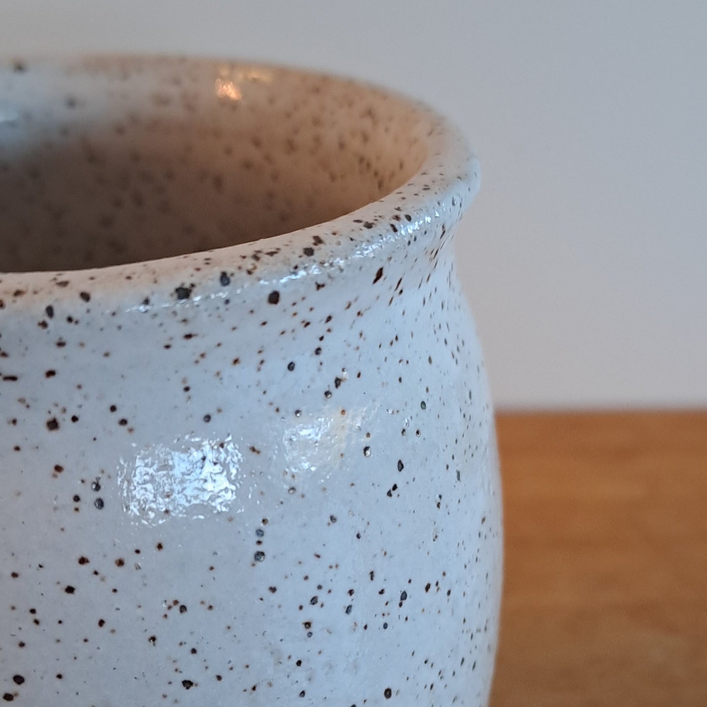 Speckled ceramic mug on a wooden surface with a neutral background