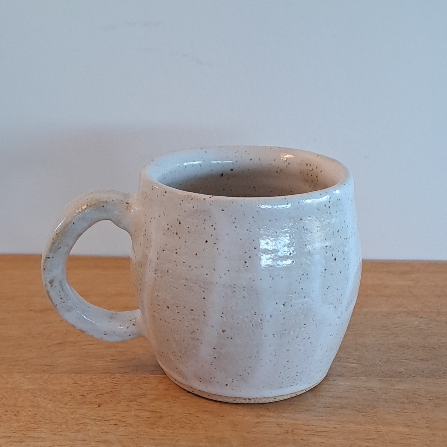 White ceramic cup with textured surface on a wooden surface