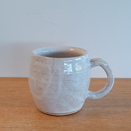 White textured mug on a wooden surface with a light gray background