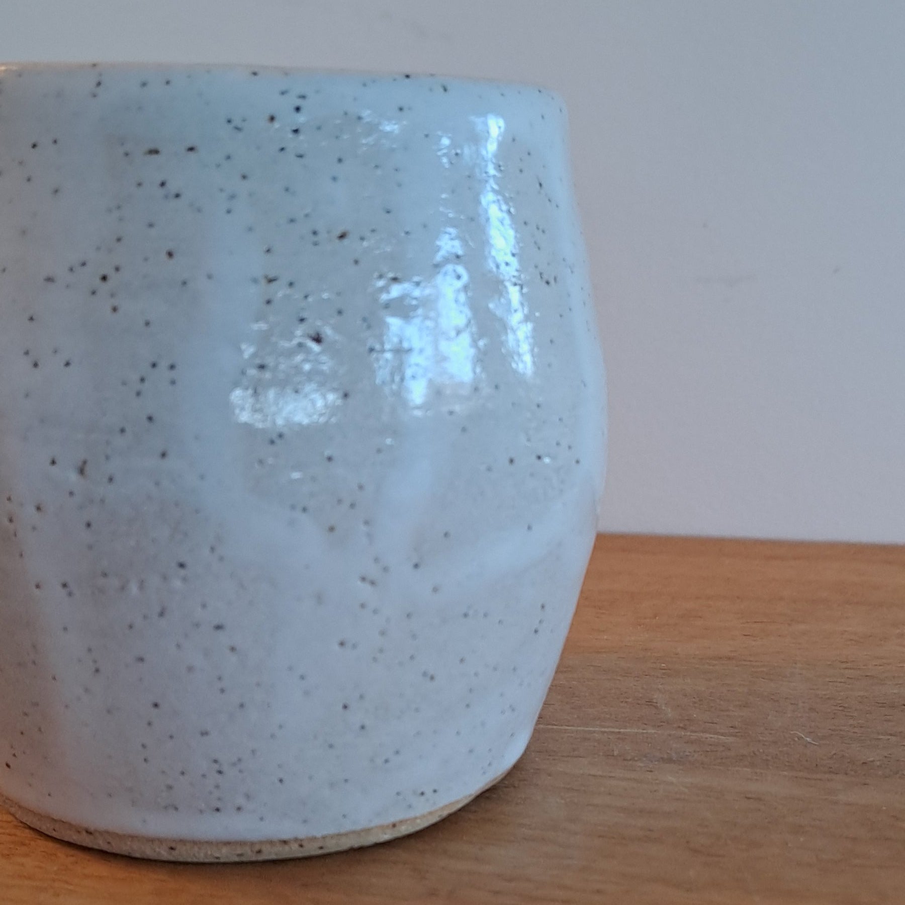 Ceramic cup with speckled pattern on a wooden surface
