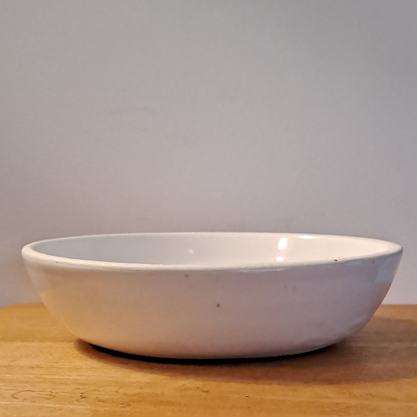White bowl on a wooden surface with a neutral background