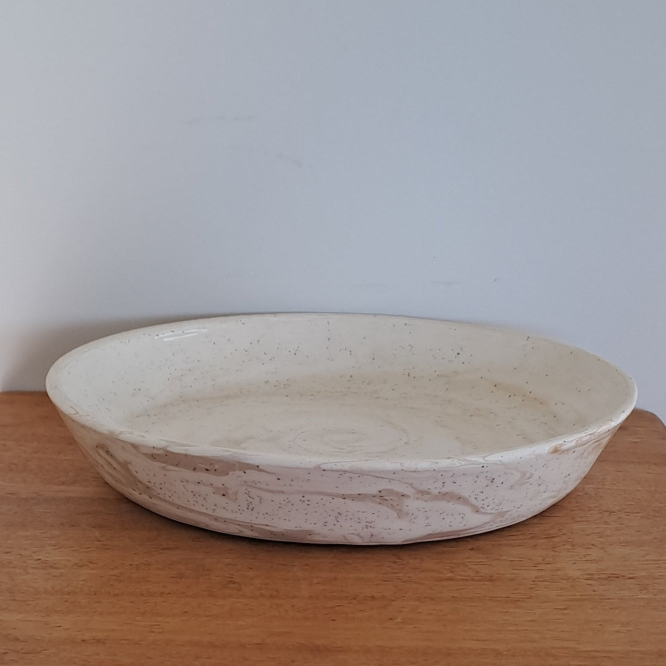 Wooden stool with a small white bowl on top against a light background