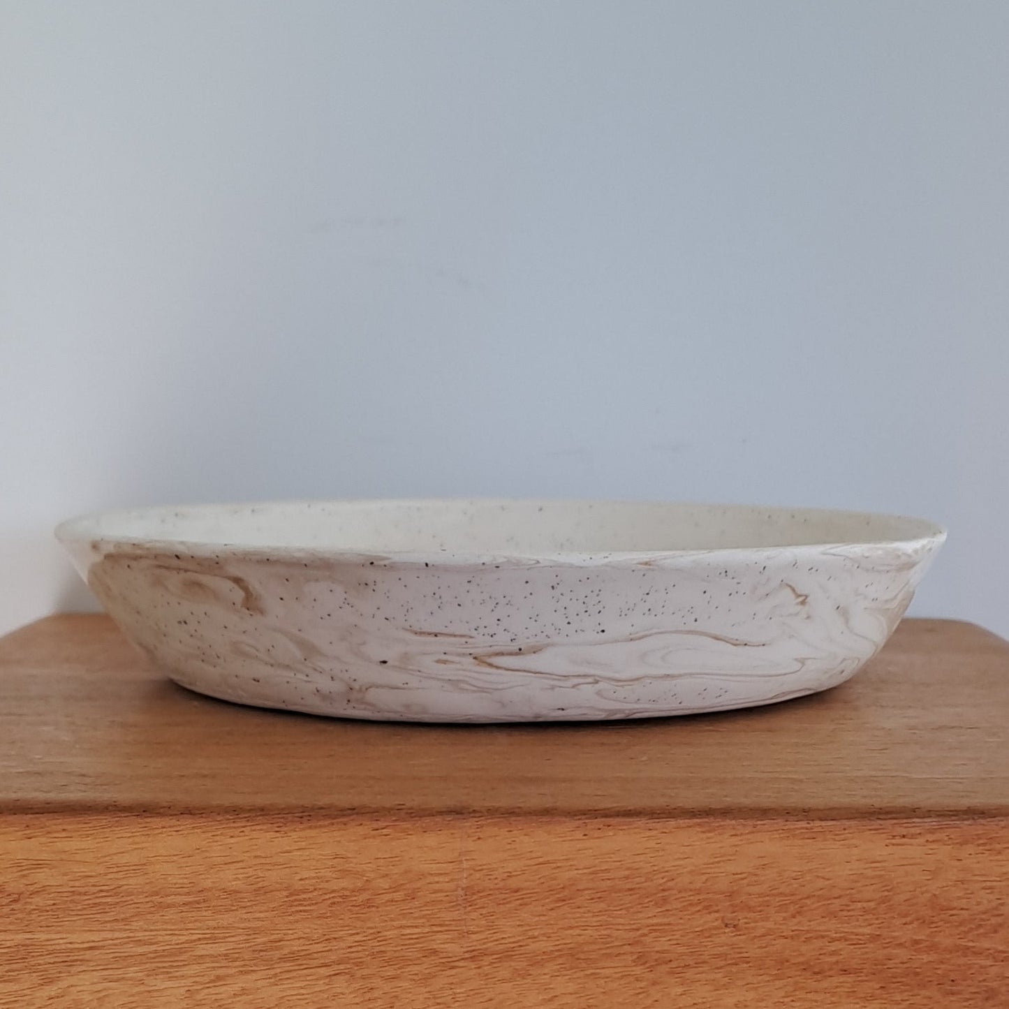Wooden stool with a small white bowl on top against a light background