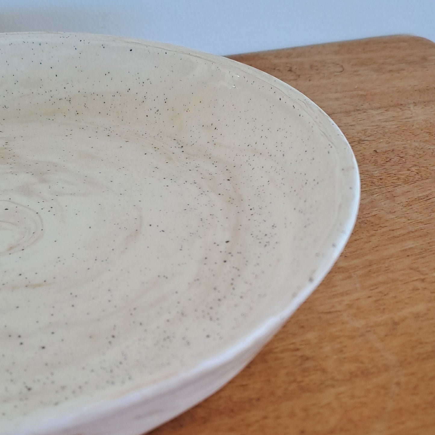 Close-up of a ceramic plate with a textured surface on a wooden surface.