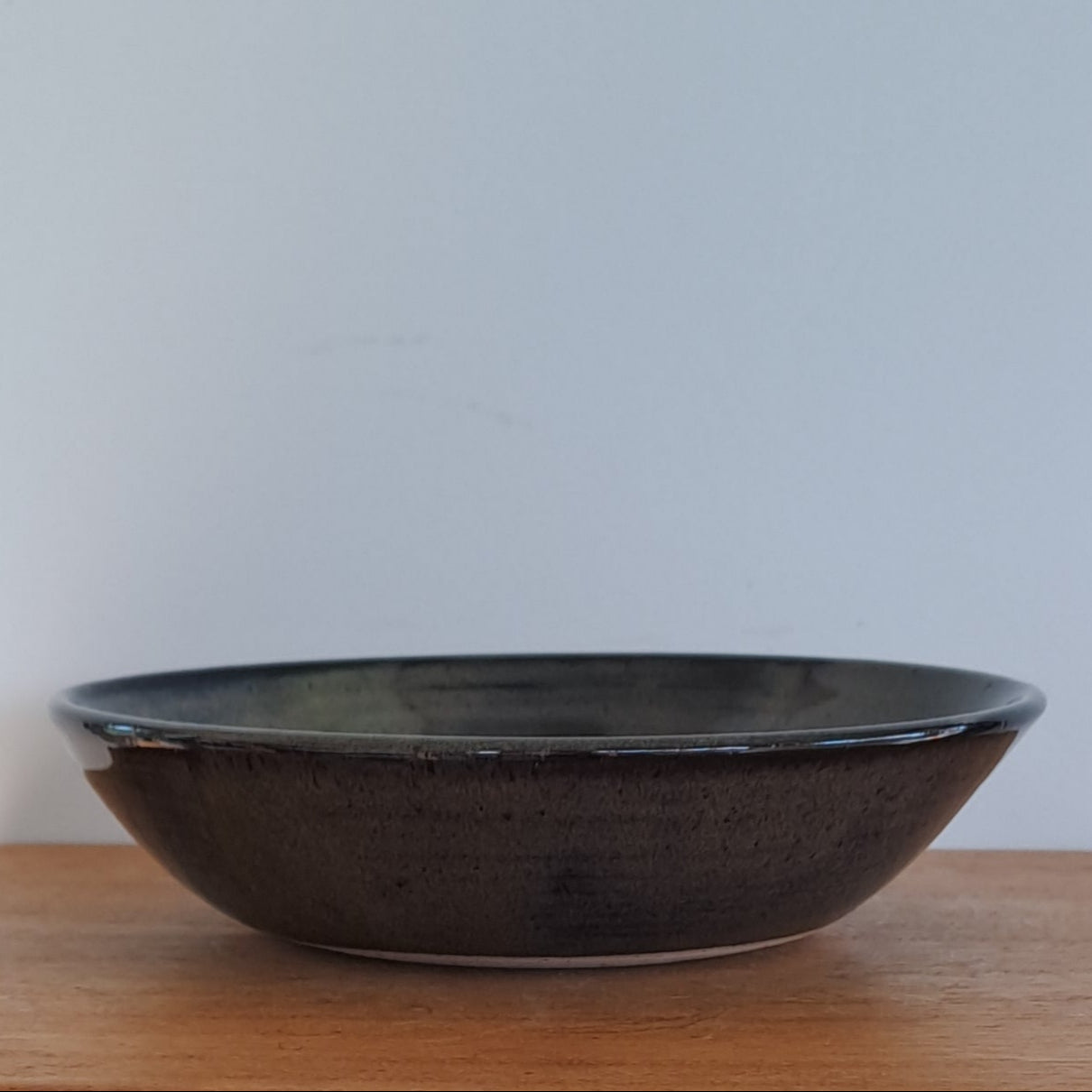 Wooden stool with a black bowl on a white surface