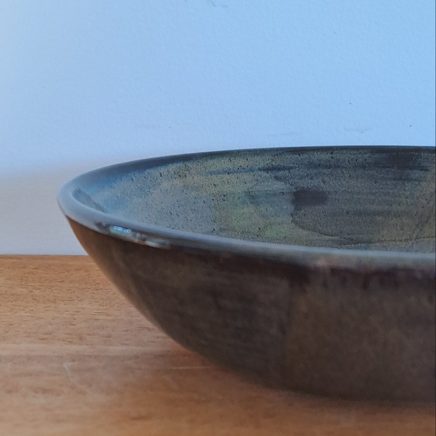 Wooden surface with a black bowl on a light blue background