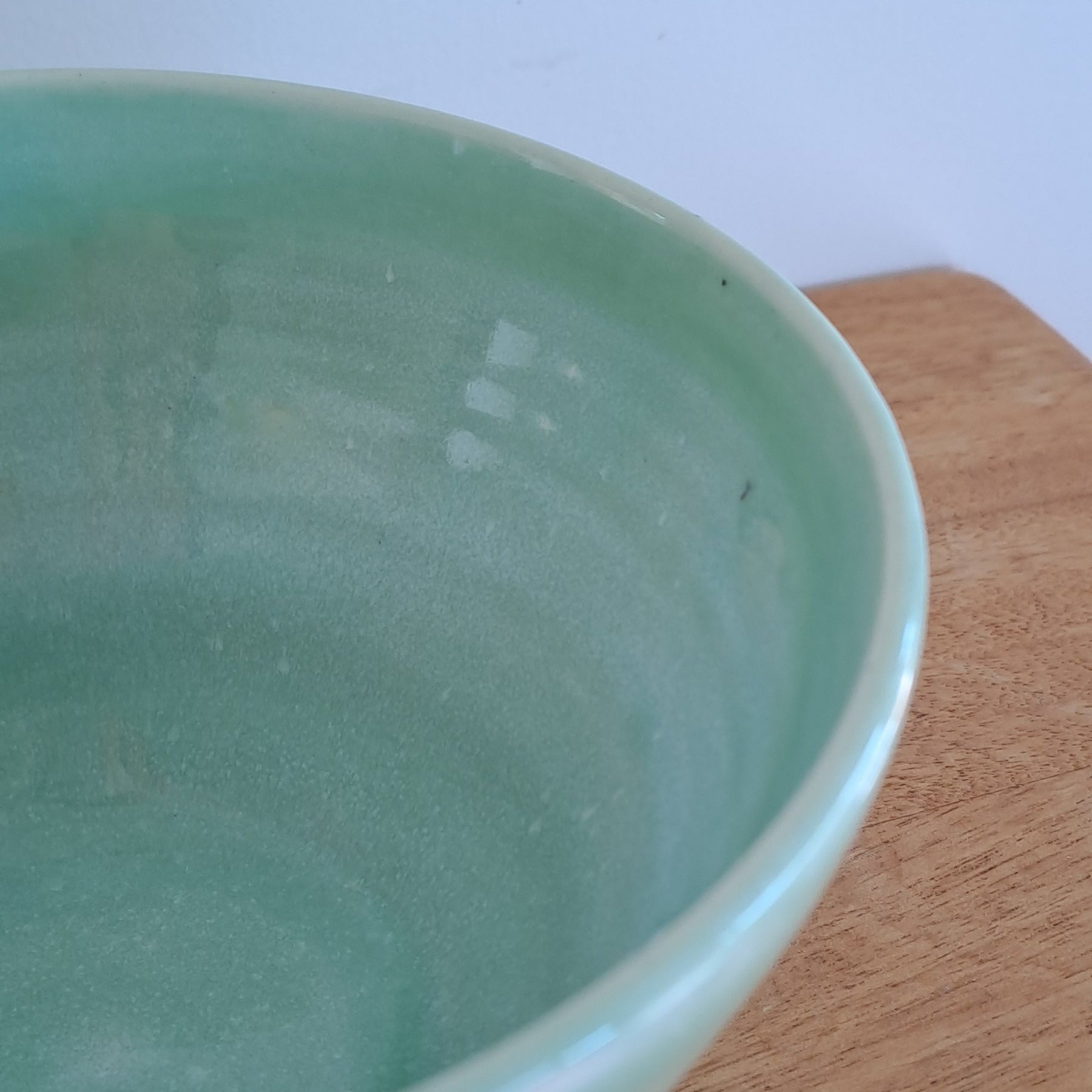 Green ceramic bowl on a wooden surface