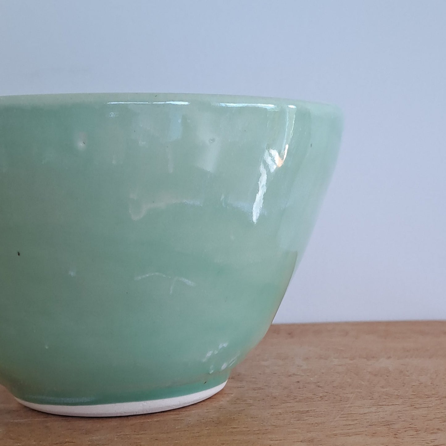 Green ceramic bowl on a wooden surface with a white background