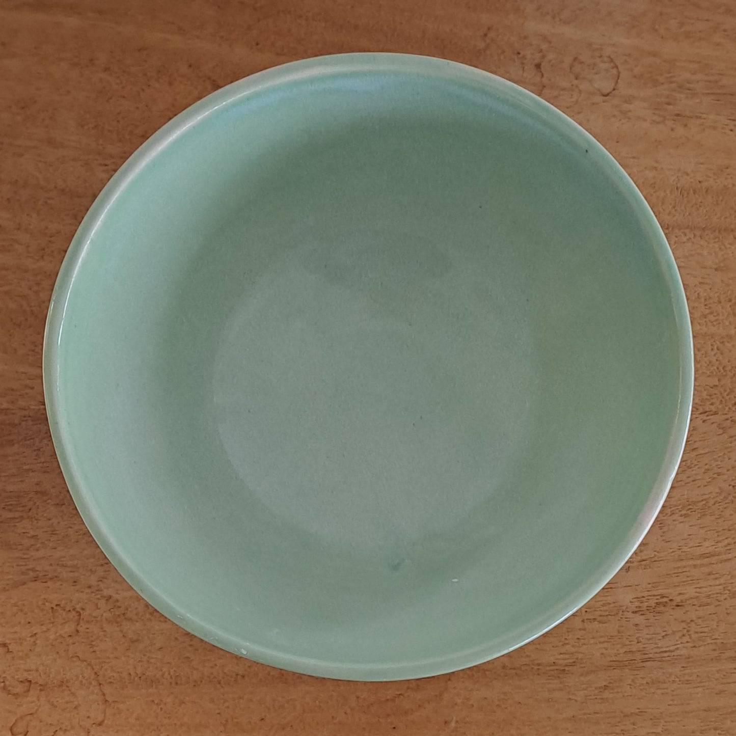 Green ceramic bowl on a wooden surface with a blurred background