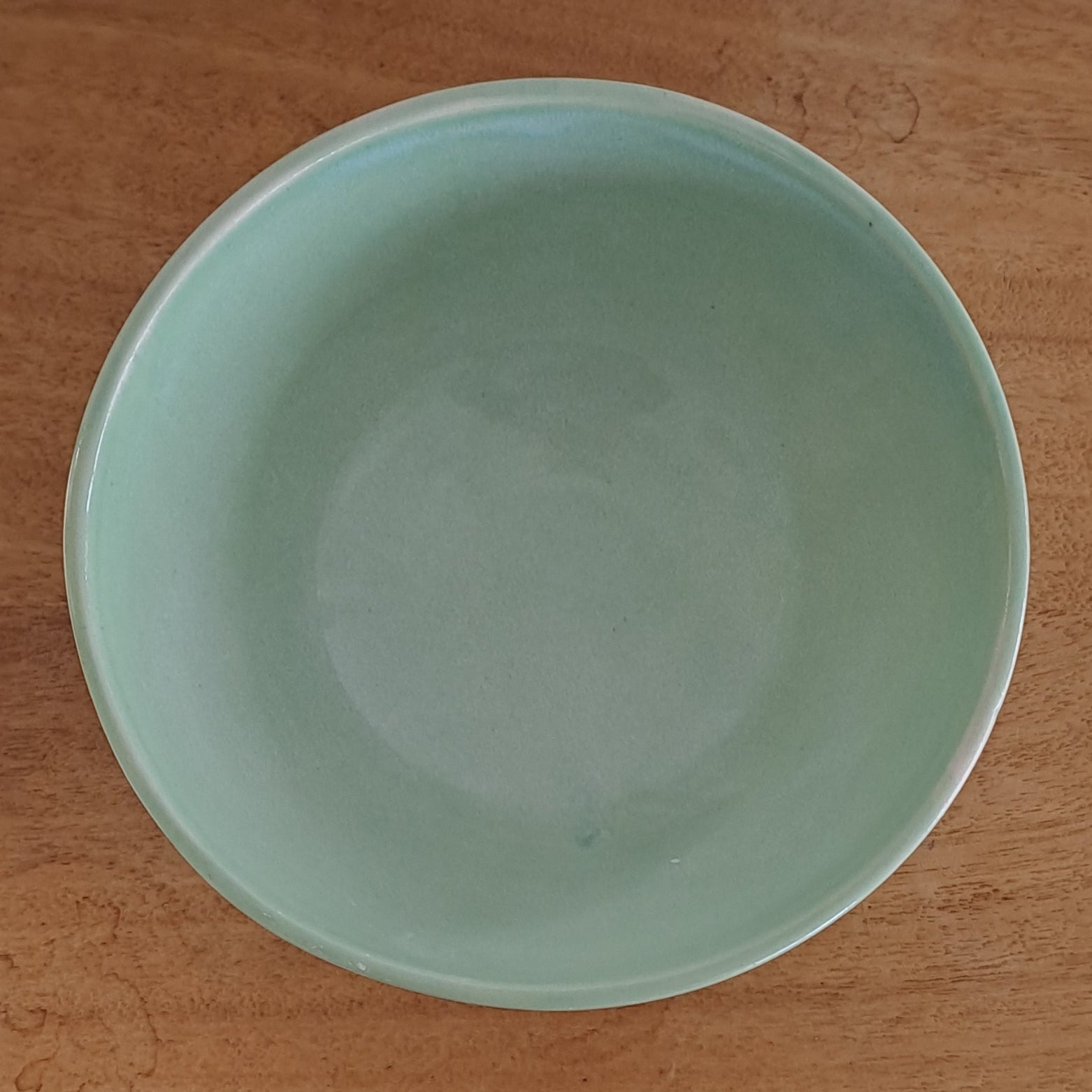 Green ceramic bowl on a wooden surface with a blurred background